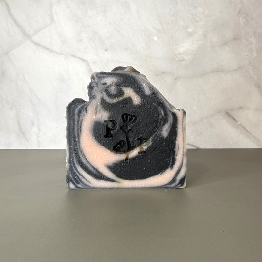 Handcrafted soap bar named Ebony Rose, deep charcoal-toned bar with subtle botanical texture, fragrance-free