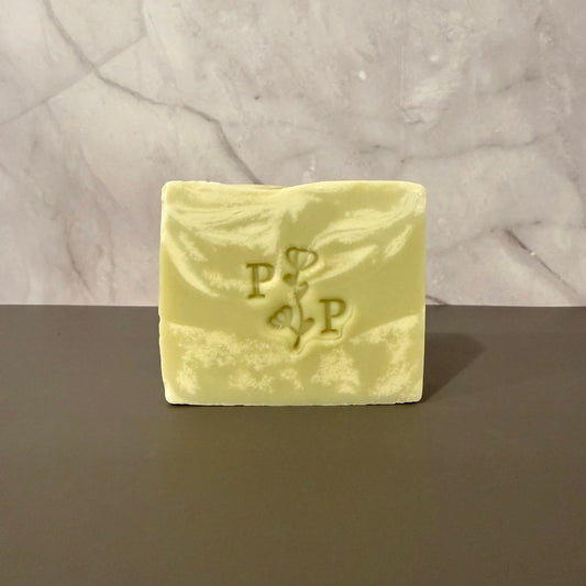 Green and cream soap bar with a logo on a gray surface and light gray background